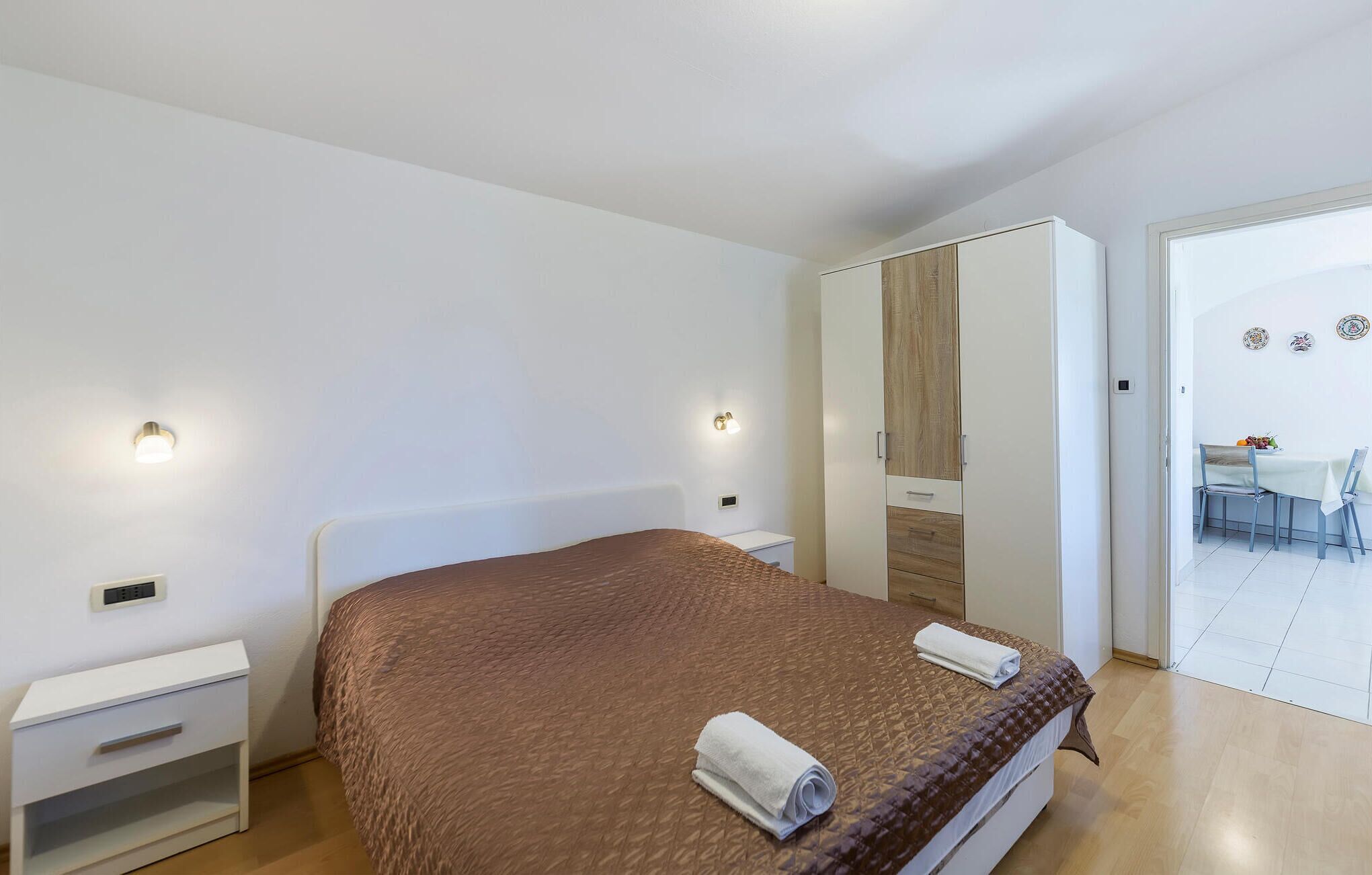 Une chambre à coucher comprenant un lit, des tables de chevet, une armoire et un coin repas avec des chaises et une table.