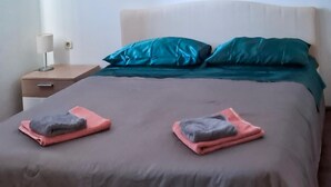 Un lit avec une couverture marron, deux oreillers et deux serviettes pliées posées sur le lit.