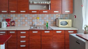 Une cuisine avec des meubles de rangement en bois, un pare-feu en carrelage, un évier et un four à micro-ondes.