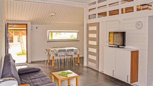 A living room with a sofa, a table with a decorative item, a TV, and a dining area with chairs and a table. - Cozy home in Mscice with WiFi (Mscice)