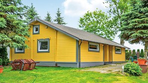 A yellow single-story house with a gabled roof, a front porch, and a small front yard with a lawn mower and garden tools. - Cozy home in Mscice with WiFi (Mscice)