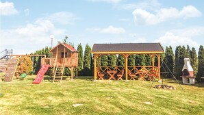 A playground with a slide, a wooden playhouse, picnic tables, and a barbecue grill. - Cozy home in Mscice with WiFi (Mscice)
