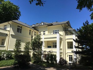 Um edifício grande e imponente, com vários andares, fachada simétrica, diversas janelas e uma entrada central.