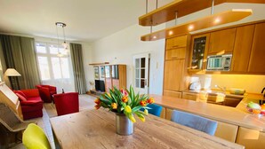 Una cocina moderna con armarios de madera, una isla central y un comedor con sillas rojas.