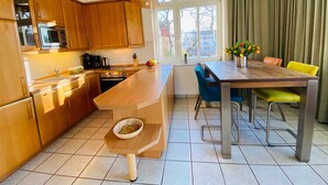 Una cocina moderna con armarios de madera, una isla central y una zona de comedor con mesa y sillas.