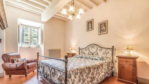Ein Schlafzimmer mit Bett, Stuhl, Fenster und einer Chandelier.
