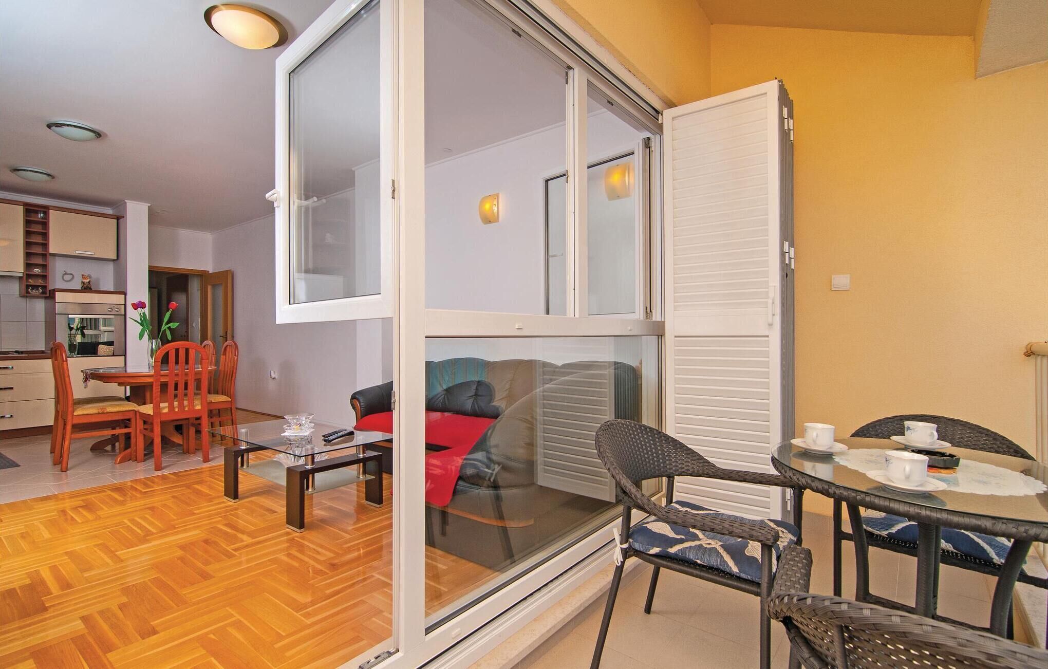 Un appartamento moderno con zona pranzo, soggiorno con divano e cucina visibile attraverso una porta in vetro.