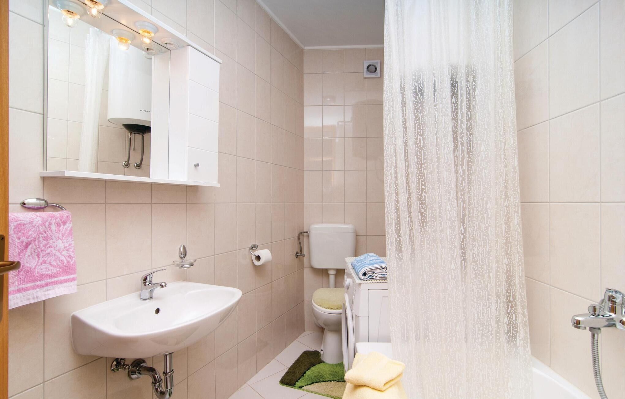 Een badkamer met een wastafel, spiegel, douche, toilet en handdoekrek.