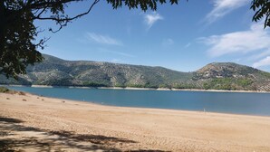 Una playa con vista despejada al agua y colinas a lo lejos.
