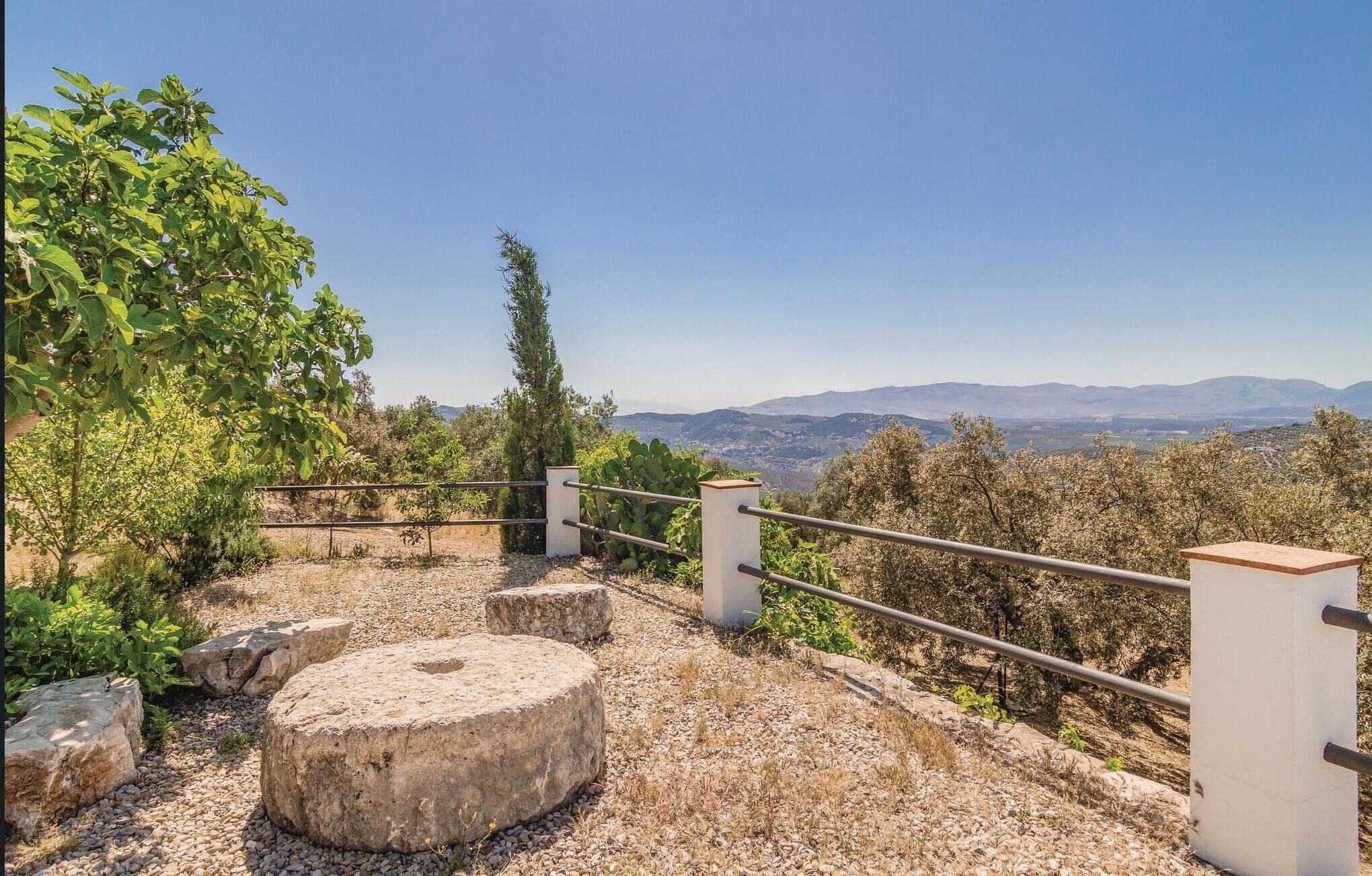 A pathway with stone steps and a metal railing, leading to a scenic overlook with a view of distant mountains.