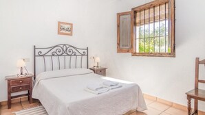 Un dormitorio con una cama, dos mesitas de noche con lámparas, una ventana y una silla.