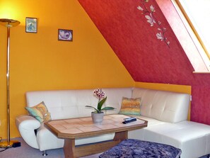 Un salon moderne avec un canapé blanc, une table basse en bois et une orchidée en pot.