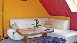 Una sala de estar moderna con un sofá blanco, una mesa de centro de madera y una orquídea en maceta.