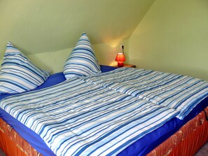 Un lit avec une literie à rayures, une table de chevet avec une lampe et un mur vert.