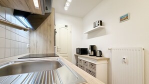 Una cocina moderna con un lavamanos de acero inoxidable, encimera de madera y electrodomésticos integrados.