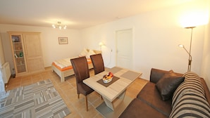 Una habitación con una mesa de comedor, sillas, un sofá, una cama, un armario y una lámpara.
