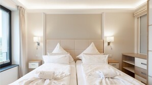 Une chambre d’hôtel avec deux lits, chacun doté d’une tête de lit, de tables de chevet, de lampes et de serviettes.