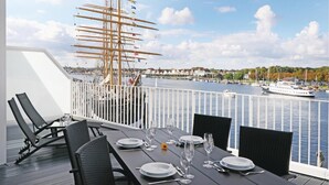 A dining area with a view of a harbor, including a tall ship and boats. - Priwallpromenade 3, Whg 11 (Travemünde Waterfront)