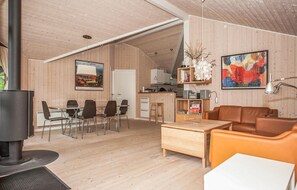 Ein geräumiger Wohnbereich mit Esstisch und Stühlen, einer Couch, einem Couchtisch, einem Kamin und einer Küchenzeile mit Spüle und Schränken.