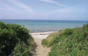 Ein Strandweg, der zum Meer führt, bei strahlend blauem Himmel.