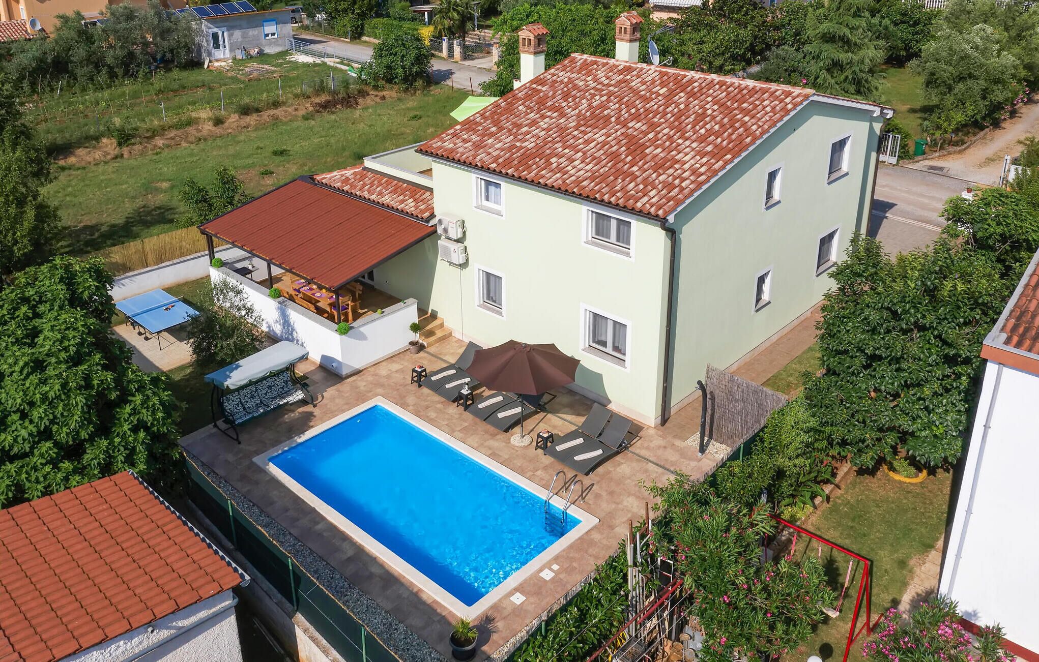 A two-story house with a swimming pool, outdoor seating, and a covered patio area.
