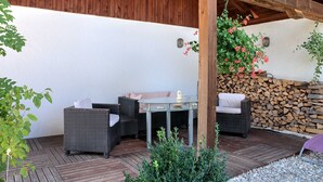 Una terrazza esterna con mobili in vimini, un tavolo in vetro e un muro in pietra.