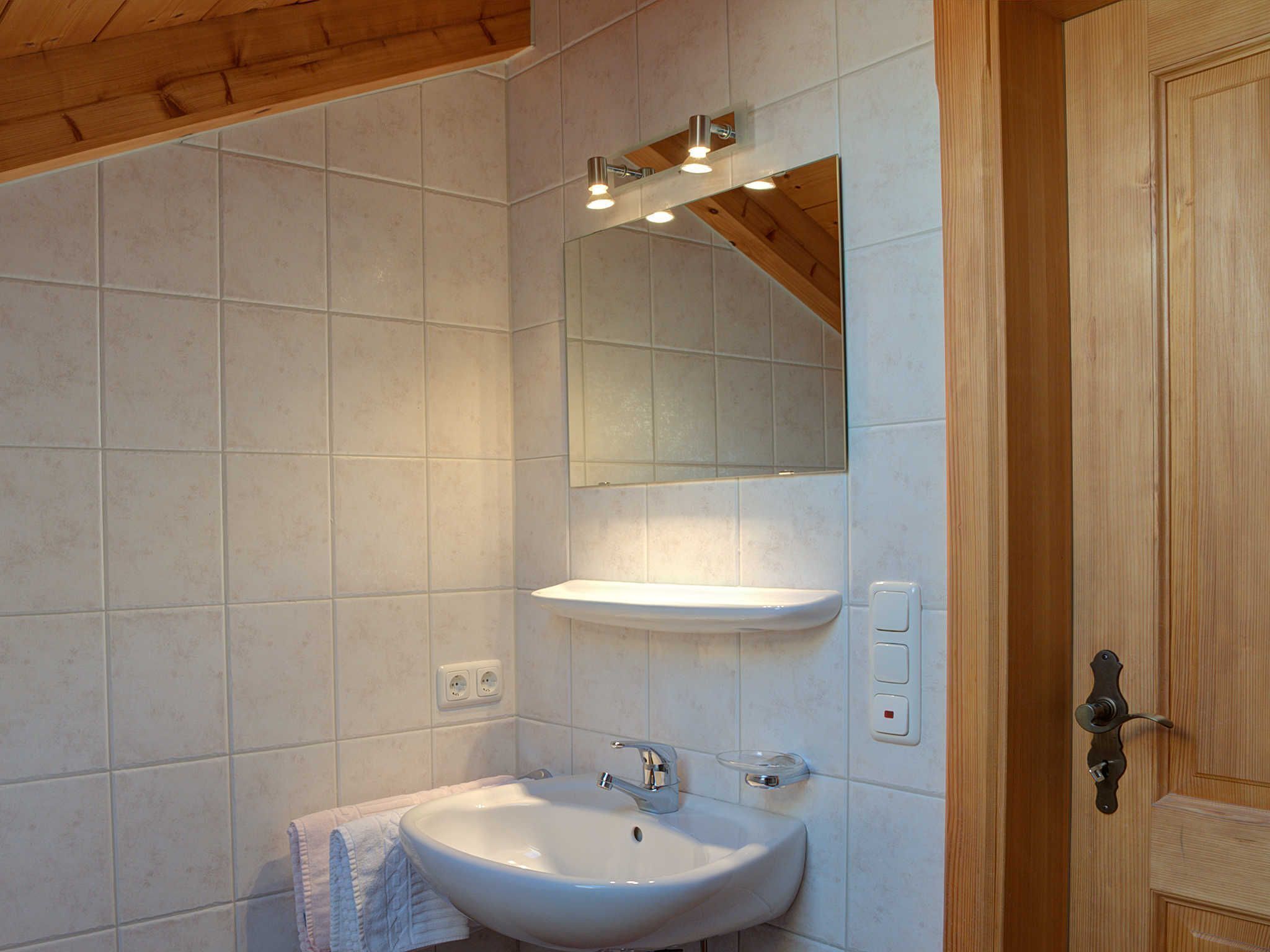 Ein Badezimmer mit Waschbecken, Spiegel und Lampenaufsatz.