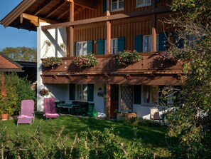 Uma casa de madeira de dois andares com uma varanda decorada com cestos de flores penduradas.