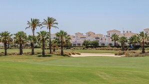 A golf course with palm trees and a building with multiple stories in the background. - Stunning home in Roldán with kitchen (Roldán)