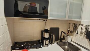 Een keuken met een ingebouwde oven, een koffiezetapparaat, een spoelbak en een serviesrek.