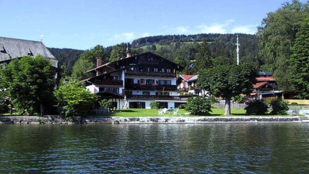 Un bâtiment situé au bord du lac, doté de nombreux balcons, d’une façade en pierre et offrant une vue sur le lac.