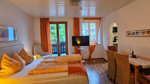 Une chambre à coucher comprenant un lit, une télévision, une table à manger avec des chaises et une vue sur l’extérieur.