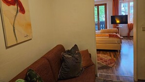 Un salon avec un canapé, un tableau, un téléviseur et une vue sur l’extérieur.