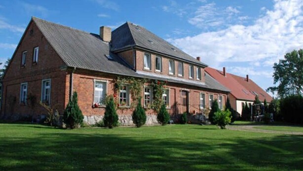 Ein großes, schmuckes Backsteinhaus mit Symmetrie, zahlreichen Fenstern und einem geneigten Dach.