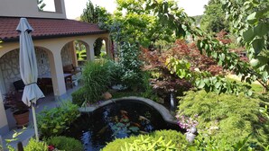 Un jardin avec un bassin, du mobilier de jardin et un espace de détente couvert.