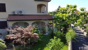 Une maison avec un jardin, un patio couvert et une vue sur la rue.