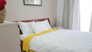 A bed with white and yellow bedding, a bedside table with a lamp, and a vase with red flowers. - Ginkgo 3 - Apartment near the sea - Apartments Ginkgo, Pula-Banjole (Banjole)
