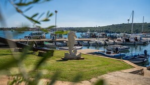 Un port de plaisance avec des bateaux amarrés, une statue et un ciel bleu azur.