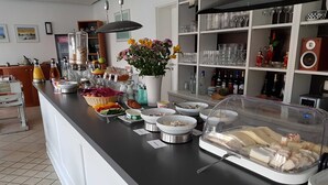 Un mostrador de buffet con diversos alimentos, un jarrón de flores y una exposición de cristalería.