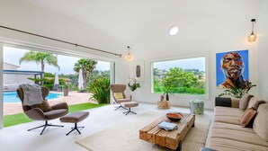 A modern living room with a pool view, a large painting, and a cozy seating area. - Stunning home in Biot (Biot)