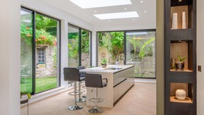 A modern kitchen with a central island, large windows, and a view of a garden. - Stunning home in Biot (Biot)