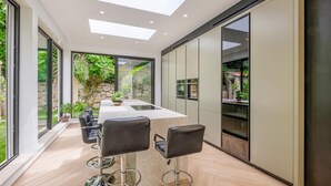 A modern kitchen with a large island, bar stools, and a view of the garden. - Stunning home in Biot (Biot)