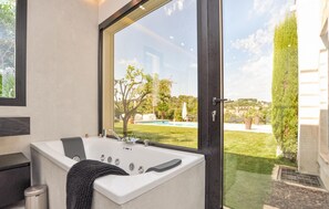 A modern bathroom with a large bathtub, a window overlooking a pool and garden. - Stunning home in Biot (Biot)