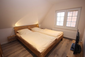 A bedroom with a wooden bed, a television, and a window with blinds.