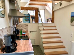 Una cocina con mostradores de madera, cafetera, estufa y ventana con vistas al exterior.