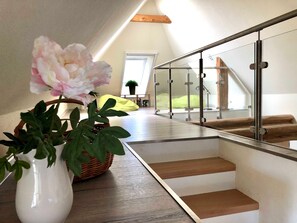 Un intérieur moderne avec un escalier, un vase blanc orné d’une fleur et un fauteuil en forme de haricot vert.