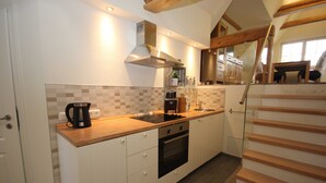 Una cocina moderna con armarios blancos, encimera de madera, horno empotrado y campana extractora de acero inoxidable.
