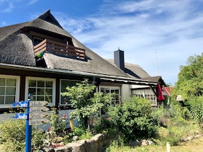 A traditional house with a thatched roof, a wooden balcony, and a stone wall.