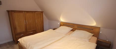Une chambre à coucher avec un lit en bois, une table de chevet, une armoire et un plafond en pente.