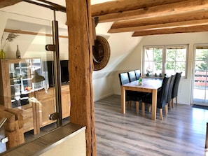 A dining area with a wooden table and chairs, a television, and a large window with a view.